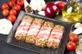 Closeup view of raw minced meat rolls wrapped with bacon and seasonings in container black plate Royalty Free Stock Photo
