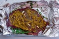 Closeup view of a raw slab of beef meat stuffed with garlic slices and covered in wholegrain mustard and spices