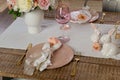 Closeup view of romantic cute table decor with glasses flowers and lit candles. Plates with flowers setup on a wooden table