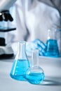 Closeup view of scientist pouring light blue liquid from test tube into flask and laboratory glassware on table, selective focus Royalty Free Stock Photo