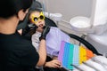 Closeup view from shoulder of female dentist examining and treats teeth of cute little child girl in funny eyeglasses Royalty Free Stock Photo