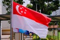 Closeup view of Singapore flag waving in the wind on bright sunny day. HDB neighbourhood in background
