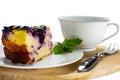 Closeup view slice of yogurt blueberry cake in white ceramic dish with a cup of coffee and metal fork