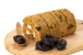 Closeup view sliced prune sponge cake roll, dried pitted prune in wooden board and in wooden spoon on white background
