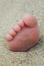 Closeup view of small feet with toes in the sand lit by the sunset light
