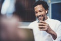 Closeup view of Smiling african man using smartphone to listen to music while sitting on the bench at sunny street Royalty Free Stock Photo