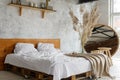 Closeup view on spacious airy white eco style loft bedroom with bed,  mirror and pampas grass decoration Royalty Free Stock Photo