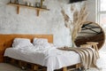 Closeup view on spacious airy white eco style loft bedroom with bed, mirror and pampas grass decoration