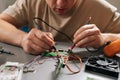 Closeup view of technician repairing electronics, inspecting and testing circuit board with multimeter while surrounded Royalty Free Stock Photo