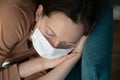 Closeup view of tired woman sleeping on a sofa in face mask