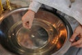 Closeup view to the priest hand holding cross and baptismal font for ceremony of the baptism of a newborn baby in Orthodox Church