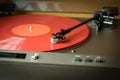 Closeup view of a tonearm and turntable playing color red vinyl record Royalty Free Stock Photo