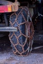 Closeup view of wheel of truck with rusty chains of safety on road
