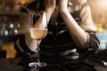 Closeup view of white wine glass on table against young adult woman sitting on ddating at cafe or restaurant at warm Royalty Free Stock Photo