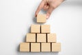 Closeup view of woman building pyramid with wooden cubes on white background. Career promotion concept Royalty Free Stock Photo