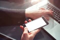 Closeup view woman hands using mobile smartphone and laptop. Space mockup for design layout. Loft interior sunlight.