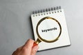 Closeup view of woman holding magnifier glass over empty notebook at grey stone table. Find keywords concept Royalty Free Stock Photo