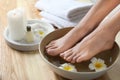 Closeup view of woman soaking her feet in dish with water and flowers. Spa treatment