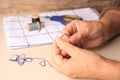 Closeup view of woman threading needle at beige table, space for text