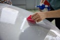 Closeup view on worker detailer hand applying protective film on car hood