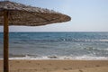 Closeup View of Woven Thatched Roof Umbrella Standing alone on the Beachfront. Footprints on Fine Sand and Wavy Crystal Royalty Free Stock Photo