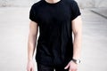 Closeup view of young muscular man wearing black tshirt and jeans posing outside. Empty background. Hotizontal mockup. Royalty Free Stock Photo