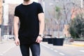 Closeup view of young muscular man wearing black tshirt and jeans posing on the street of the modern city. Blurred Royalty Free Stock Photo