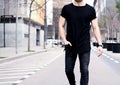 Closeup view of young muscular man wearing black tshirt and jeans walking on the streets of the modern city. Blurred Royalty Free Stock Photo