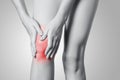 Closeup view of a young woman with knee pain on gray background. Royalty Free Stock Photo