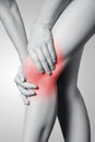 Closeup view of a young woman with knee pain on gray background. Royalty Free Stock Photo