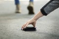 Close up view of young woman picking up lost wallet on city street, empty space