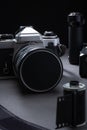 Closeup of vintage 35mm SLR-type film camera with a battery grip. And old metallic film cartridge against a dark background Royalty Free Stock Photo