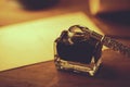 Closeup of vintage quill pen and ink jar on wooden table