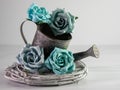 Closeup of a vintage silver watering pot decorated with blue roses against a grey blurry background Royalty Free Stock Photo