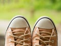 Closeup of vintage soft brown woman sneaker shoes on blur green nature in background. Travel adventure and journey concept