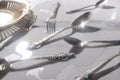 Closeup of shiny silver kit of spoons, forks, vintage plate on the wet white table.Concept of luxury event in the evening Royalty Free Stock Photo