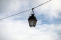 vintage street light suspended on cable in the street on cloudy sky background