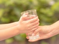 Closeup vintage woman hand giving glass of fresh water to child in the park. Royalty Free Stock Photo