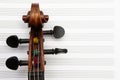 Closeup of violin head stock against blurry staff paper background Royalty Free Stock Photo