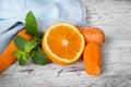 Closeup of vivid orange, slices of carrot and sappy green leaves of mint on a light wooden background. Royalty Free Stock Photo