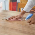 Closeup waiter`s hand use a liquid cleaner and a towel to wipe off the stains on the table