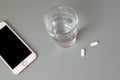 Closeup of cellphone, water and headache tablets Royalty Free Stock Photo