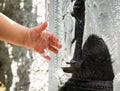 Closeup water flow of fountain to hand of baby playing for nature concept on the garden background