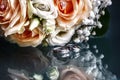 Closeup of a wedding bouquet next to wedding rings on glass Royalty Free Stock Photo