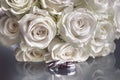 Closeup of a wedding bouquet next to wedding rings on glass Royalty Free Stock Photo