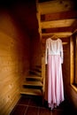 Closeup of the wedding dress hanging at wooden stairs