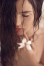 Closeup wet woman portait with plumeria tropical flower in the hand. Shampoo.