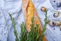 Closeup of wheat baguette, twigs of fragrant rosemary, little quail eggs on a light gray background.