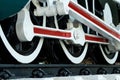 Closeup wheel of train. Green red and white train. Antique vintage train locomotive. Old steam engine locomotive. Black locomotive