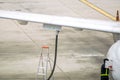 Closeup white airplane parked and refueling on ground in the airport with ground staff fixing Royalty Free Stock Photo